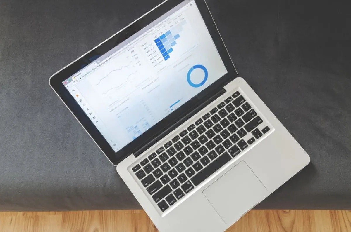 An open laptop on a grey sofa showing a dashboard of charts and graphs